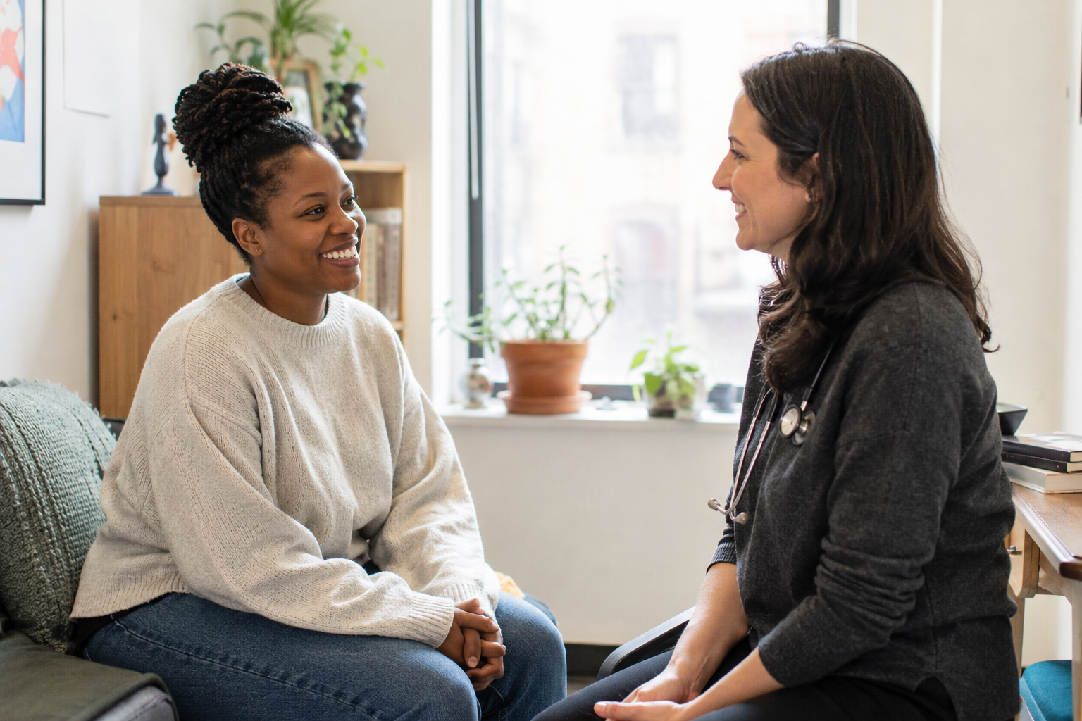 A Brooklyn patient smiling with her primary care provider in a warm, daylit room